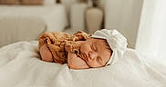 Alyzée a rejoint le concours — aidez-le/la à gagner de superbes lots ! baby, sleeping, infant, headband, bow, blanket, brown_outfit, soft_light, cozy, indoors, bedroom, peaceful, newborn, cute, portrait, child, resting, white, fabric, calm