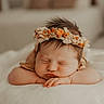 baby, newborn, sleeping, flower_crown, infant, face, skin, peaceful, closeup, portrait, soft_light, cute, child, resting, hands, headband, indoors, warm_tones, blanket, adorable