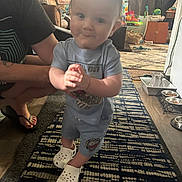 Brentlee is registered to the contest to win money with this photo: toddler, child, person, indoor, carpet, clothing, shoes, adult, living_room, window, furniture, pet_bowls, toy, floor, smile, hair, hand, footwear, support, home