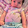 baby, infant, child, portrait, sitting, lying_down, wide_eyes, dark_hair, smiling, pink_outfit, denim_pants, blanket, cozy, indoors, nursery, soft_lighting, closeup, face, photography, finger