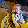 baby, child, infant, portrait, smiling, pacifier, sitting, highchair, plush_toy, yellow_toy, toy, playroom, indoor, brick_wall, cushion, blanket, floral_clothing, hair_bow, computer, cozy