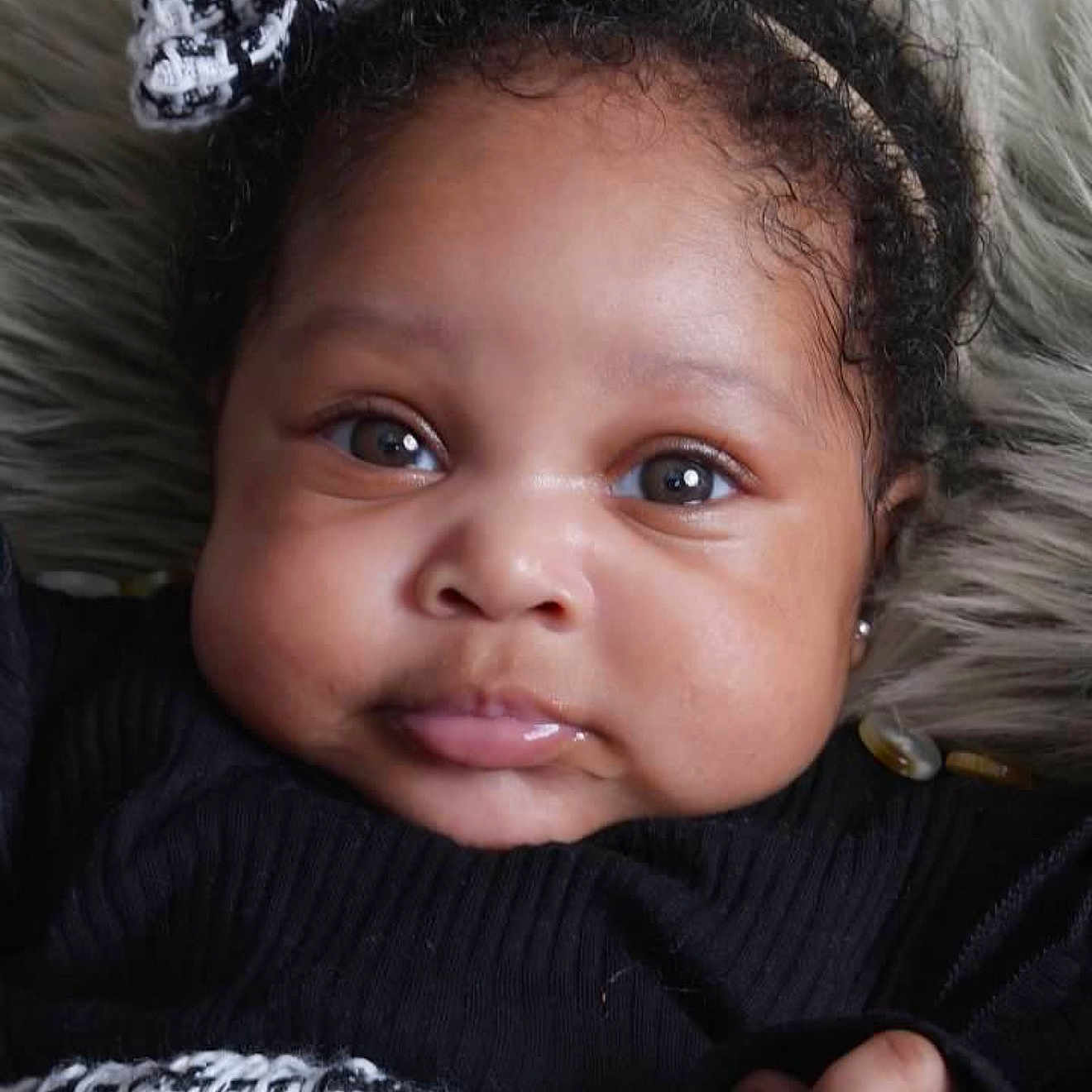 Siyah Porter joined the competition — help win amazing prizes! baby, black_clothing, child, chubby_cheeks, closeup, cozy, curly_hair, cute, eyes, face, furry_background, hand, headband, indoors, infant, person, portrait, skin, soft_texture, white_pattern