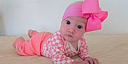 Dahlia joined the competition — help win amazing prizes! baby, infant, child, pink_bow, headband, checkered_onesie, tummy_time, lying_on_stomach, portrait, wide_eyes, hands, skin, bed_sheet, indoor, cute, newborn, fashion_accessory, hat, pink_clothing, soft_lighting