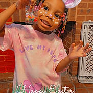 Janiya is registered to the contest to win money with this photo: child, girl, smiling, easter, bunny_ears_filter, beads, candy, pink_shirt, brick_wall, decoration, indoor, carpet, toy, happy, posing, face_paint, festive, holiday, colorful, young