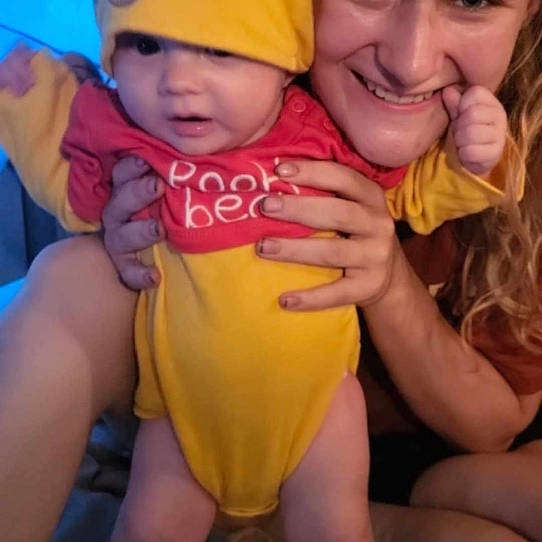 Valentino joined the competition — help win amazing prizes! apparel, baby, child, cute, expression, face, happy, holding, hood, human, indoor, person, pooh_bear, portrait, red_clothing, skin, smile, toddler, woman, yellow_clothing