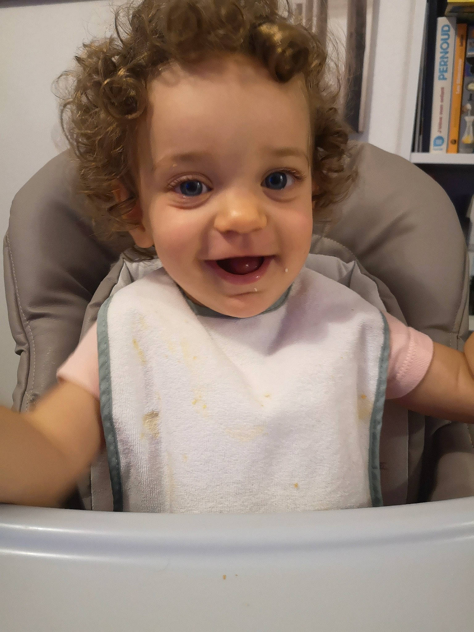 Andrea participe au concours pour gagner de l'argent avec cette photo : arm, baby, bookcase, cheek, chin, facial_expression, finger, gesture, happy, head, iris, joy, lip, mouth, nose, person, shelf, skin, sleeve, smile