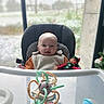 baby, high_chair, bib, toy, elf_doll, indoor, window, snow, winter, child, smile, face, seat, colorful, plastic_toy, person, holiday, christmas, decor, cute