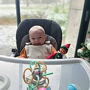 Lysio a rejoint le concours — aidez-le/la à gagner de superbes lots ! baby, high_chair, smiling, toy, elf_doll, indoor, window, face, child, seat, colorful, holiday, festive, person, plastic_toy, smile, infant, clothing, background, home