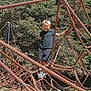 child, boy, playground, climbing_structure, rope, outdoor, daylight, tree, greenery, blue_sky, smiling, casual_clothing, shorts, tshirt, shoes, fun, recreation, active, summer, park