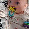 Aspyn is registered to the contest to win money with this photo: apparel, baby, baby_toy, blanket, child, closeup, colorful, cute, expression, face, indoor, infant, lying_down, onesie, pacifier, pattern, portrait, sleepwear, toy, young