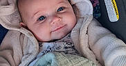 Aspyn is registered to the contest to win money with this photo: baby, blanket, blue_eyes, car_seat, child, clothing, comfort, cozy, cute, expression, face, indoors, infant, jacket, portrait, resting, smiling, soft_light, toddler, warm