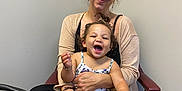 Kyelynn joined the competition — help win amazing prizes! woman, child, toddler, laughing, smiling, indoor, armchair, casual_clothing, butterfly_swimsuit, pink_shoes, wooden_chair, happy, family, mother_and_child, affection, candid, joy, hair_bun, bracelet, skin_tone