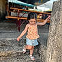 child, girl, stairs, concrete, outdoor, summer_clothing, sandals, top, shorts, playing, daylight, holding, pillar, background, bench, flags, smiling, cute, hair, walking