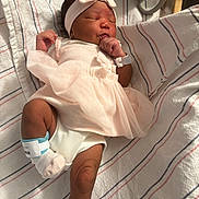Demi Lynn is registered to the contest to win money with this photo: ankle_monitor, baby, blanket, bow, closed_eyes, face, feet, hands, headband, hospital, indoors, infant, newborn, photography, pink_outfit, portrait, resting, sleeping, striped_bedding, wristband