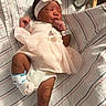 ankle_monitor, baby, blanket, bow, closed_eyes, face, feet, hands, headband, hospital, indoors, infant, newborn, photography, pink_outfit, portrait, resting, sleeping, striped_bedding, wristband