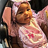 baby, bib, bow, car_seat, child, cute, eyes, face, fashion, floral, headband, indoors, infant, looking_at_camera, photography, pink_clothing, portrait, seated, smiling, vehicle