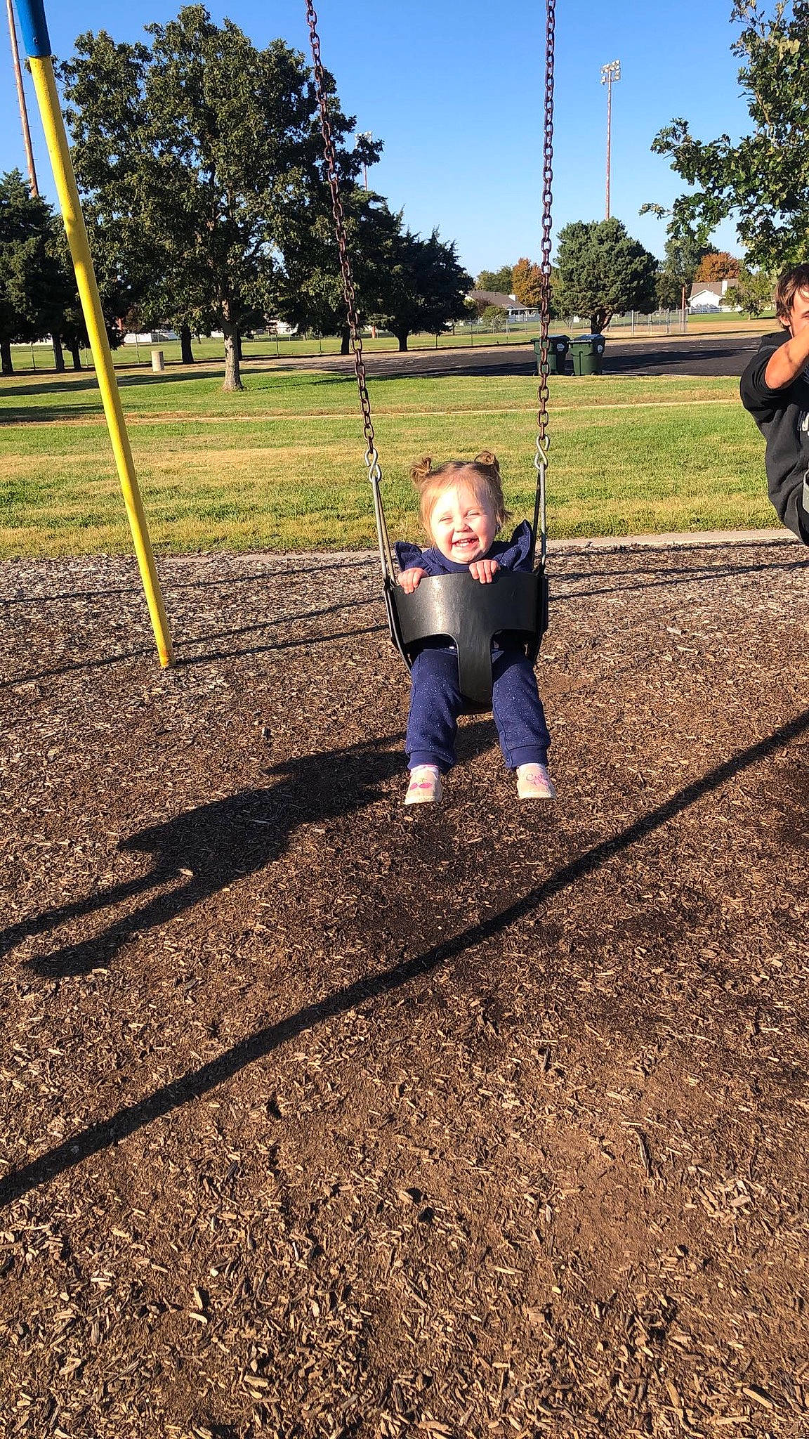 Payten is registered to the contest to win money with this photo: child, city, fun, grass, human_settlement, joy, leisure, outdoor_play_equipment, park, person, plant, play, playground, public_space, recreation, sky, smile, soil, swing, toddler