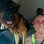 car, dog, earbuds, flower, german_shepherd, glasses, happy, head, interior, necklace, pet, seat, seatbelt, selfie, smile, sunlight, tattoo, tongue_out, window, woman