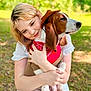 woman, dog, hugging, outdoor, cowboy_hat, bandana, pet, affection, nature, greenery, sunlight, casual_clothing, white_dress, brown_and_white_dog, close_up, portrait, smiling, animal, friendship, relaxation