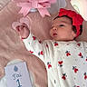Camelia a rejoint le concours — aidez-le/la à gagner de superbes lots ! baby, infant, onesie, red_bow, pink_blanket, flowers, bouquet, milestone_card, soft_texture, cute, sleepwear, newborn, lying_down, hand, face, celebration, decor, heart_pattern, portrait, indoors