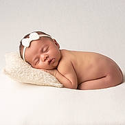 Romie participe au concours pour gagner de l'argent avec cette photo : newborn, baby, sleeping, headband, pillow, naked, infant, soft_texture, white_background, peaceful, cute, portrait, resting, child, toddler, minimalist, studio, closeup, skin, relaxation