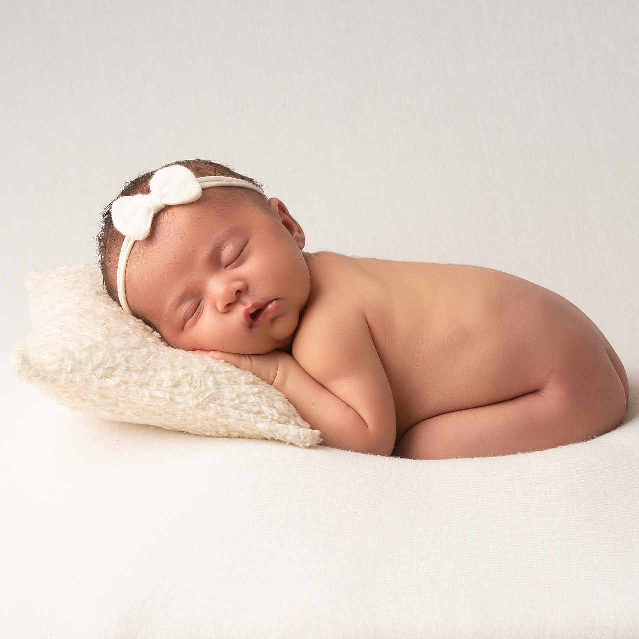 Romie participe au concours pour gagner de l'argent avec cette photo : newborn, baby, sleeping, headband, pillow, naked, infant, soft_texture, white_background, peaceful, cute, portrait, resting, child, toddler, minimalist, studio, closeup, skin, relaxation
