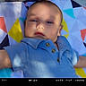 Jacob is registered to the contest to win money with this photo: baby, infant, blue_shirt, colorful_blanket, geometric_pattern, soft_light, shadow, portrait, face, child, outdoor, cute, young, lying_down, fabric, closeup, casual_clothing, summer, resting, film_frame