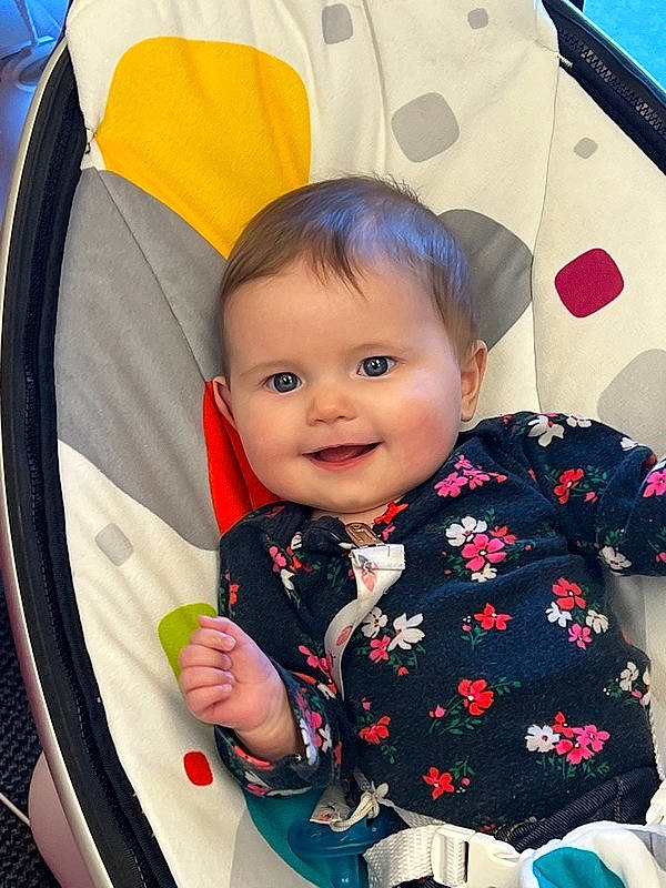 Hope is registered to the contest to win money with this photo: baby, baby_products, baby_toddler_clothing, child, event, facial_expression, fun, hairstyle, happy, joy, outerwear, pattern, person, photograph, product, recreation, sitting, skin, sleeve, smile