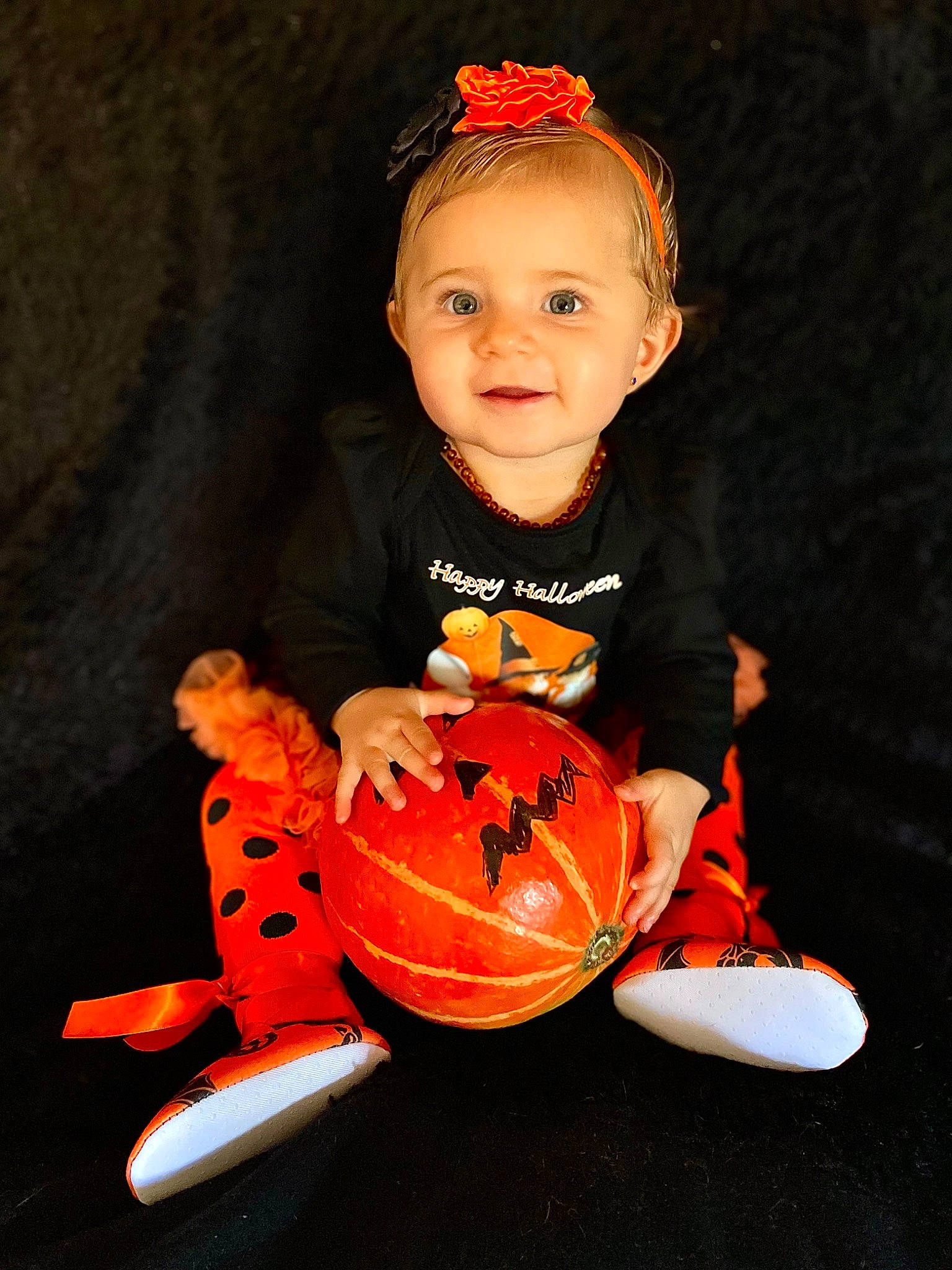 Molly participe au concours pour gagner de l'argent avec cette photo : baby, baby_toddler_clothing, calabaza, carmine, child, fashion_accessory, flash_photography, happy, headband, headpiece, jewellery, joy, orange, person, personal_protective_equipment, sitting, sleeve, smile, t_shirt, toddler