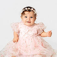 Luna is registered to the contest to win money with this photo: baby, child, girl, smiling, sitting, dress, pink, floral, headband, pearls, cute, portrait, infant, happy, barefoot, studio, white_background, cute_expression, fashion, adorable