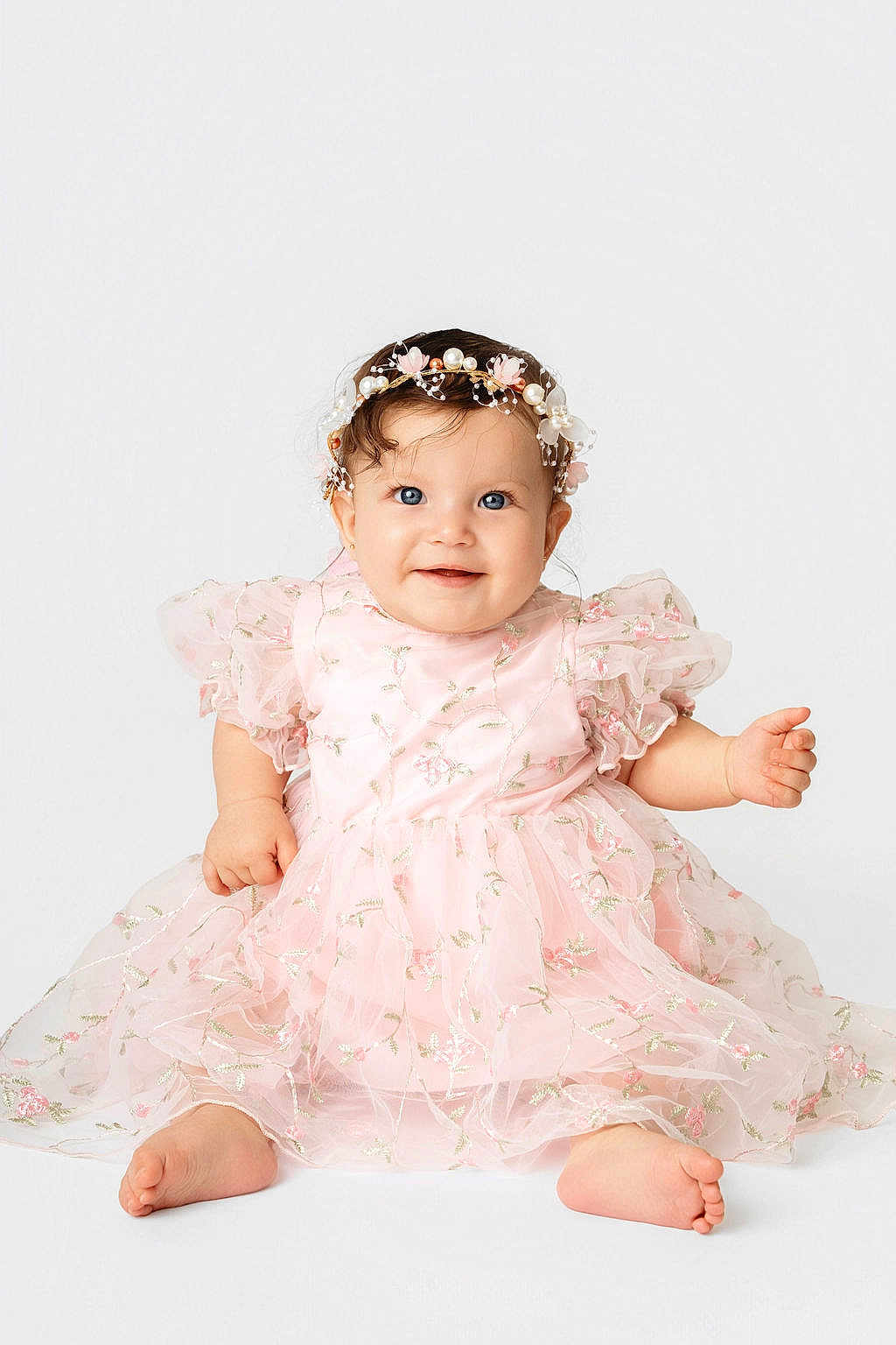 Luna is registered to the contest to win money with this photo: baby, child, girl, smiling, sitting, dress, pink, floral, headband, pearls, cute, portrait, infant, happy, barefoot, studio, white_background, cute_expression, fashion, adorable