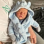 baby, newborn, sleeping, hooded_robe, blue_clothing, couch, person, hand, cozy, indoor, soft_fabric, infant, cute, warm, relaxing, toddler, child, comfort, rest, casual