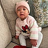 Sariyah is registered to the contest to win money with this photo: baby, child, pink_hat, knit_hat, striped_sweater, minnie_mouse, red_shoes, white_leggings, polka_dot_leggings, beige_couch, patterned_cushion, indoor, sitting, cute, portrait, cozy, soft_texture, looking_at_camera, small_hands, warm_clothing