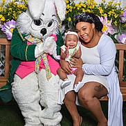 Sariyah is registered to the contest to win money with this photo: baby, bench, bunny_costume, clapping, costume, family, flowers, fun, garden, green_grass, happy, headband, outdoor, person, photography, playful, smile, spring, tattoo, woman