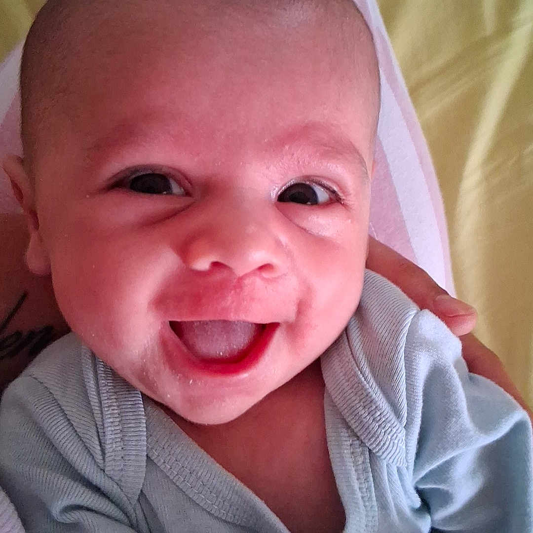 Djianny participe au concours pour gagner de l'argent avec cette photo : baby, blanket, blue_outfit, closeup, clothing, cute, expression, eyes, face, hand, happy, head, holding, indoors, infant, mouth, person, portrait, skin, smiling