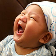 Evan is registered to the contest to win money with this photo: baby, laughing, head_wrap, chubby_cheeks, infant, blue_clothing, happy, portrait, closeup, expression, cute, child, smile, indoors, sitting, skin, face, mouth_open, young, headwear