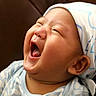 baby, laughing, head_wrap, chubby_cheeks, infant, blue_clothing, happy, portrait, closeup, expression, cute, child, smile, indoors, sitting, skin, face, mouth_open, young, headwear