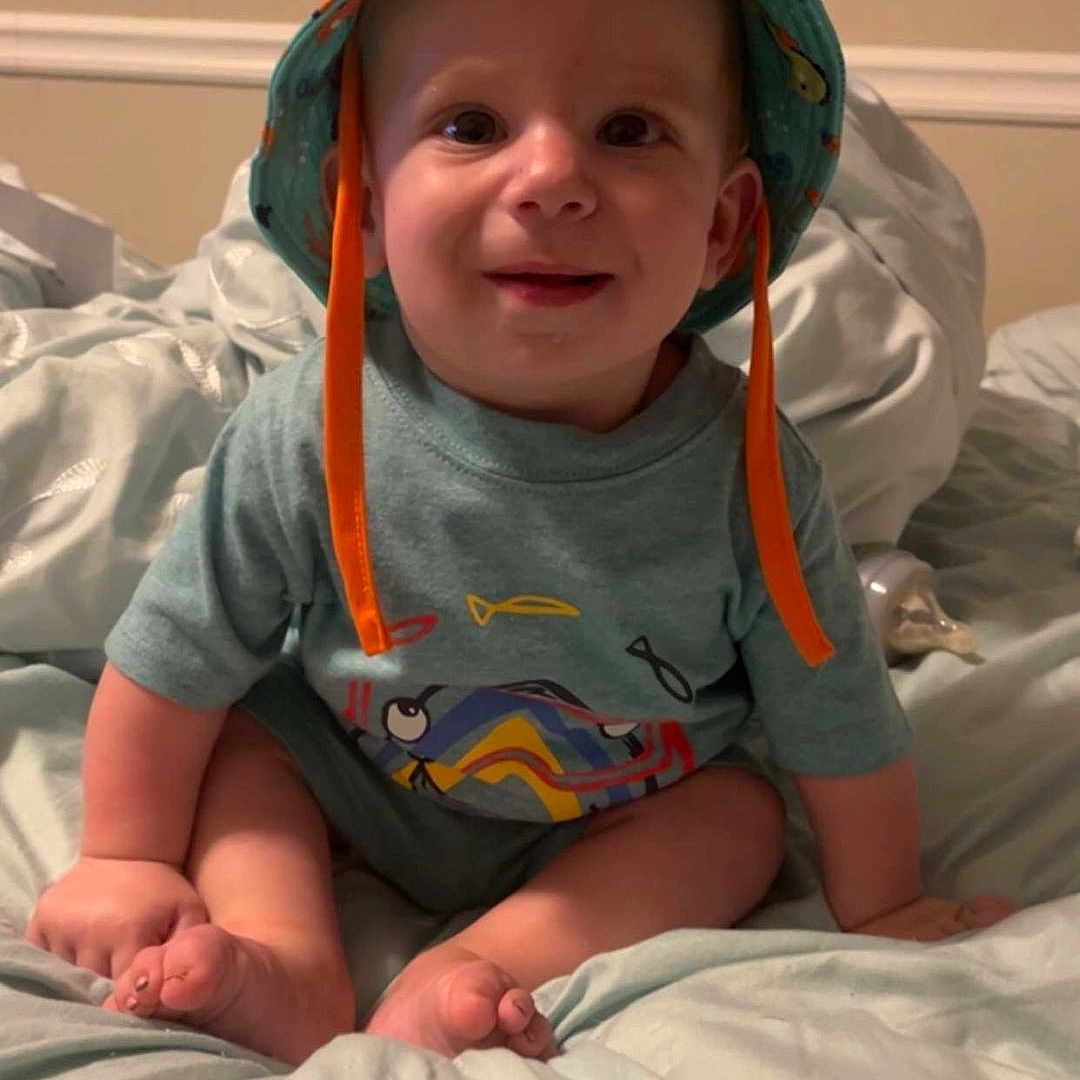 Gavin joined the competition — help win amazing prizes! baby, baseballcap, bed, bedroom, clothing, cushion, face, furniture, happy, hat, head, homedecor, indoors, person, photography, portrait, room, sitting, smile, t_shirt