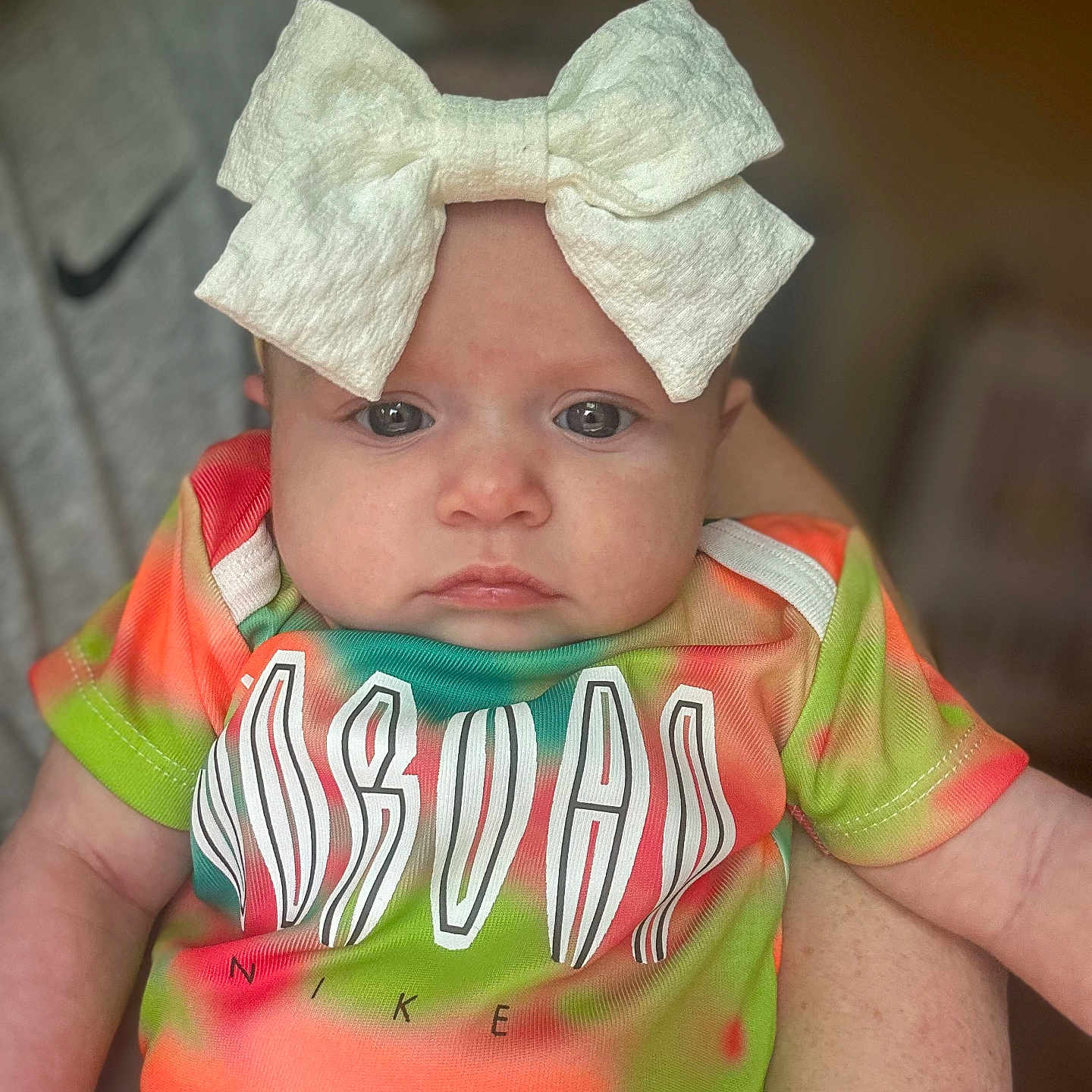 Ila Jayde is registered to the contest to win money with this photo: arm, baby, blurred_background, bow, child, colorful_clothing, cute, face, hand, headwear, holding, indoor, infant, jordan, nike, person, portrait, serious_expression, skin, tshirt