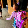 child, girl, backpack, purple, hello_kitty, bow, hair, jeans, walking, side_view, school, corridor, concrete_floor, brick_wall, window, adult, tattoo, casual_clothing, footwear, daylight