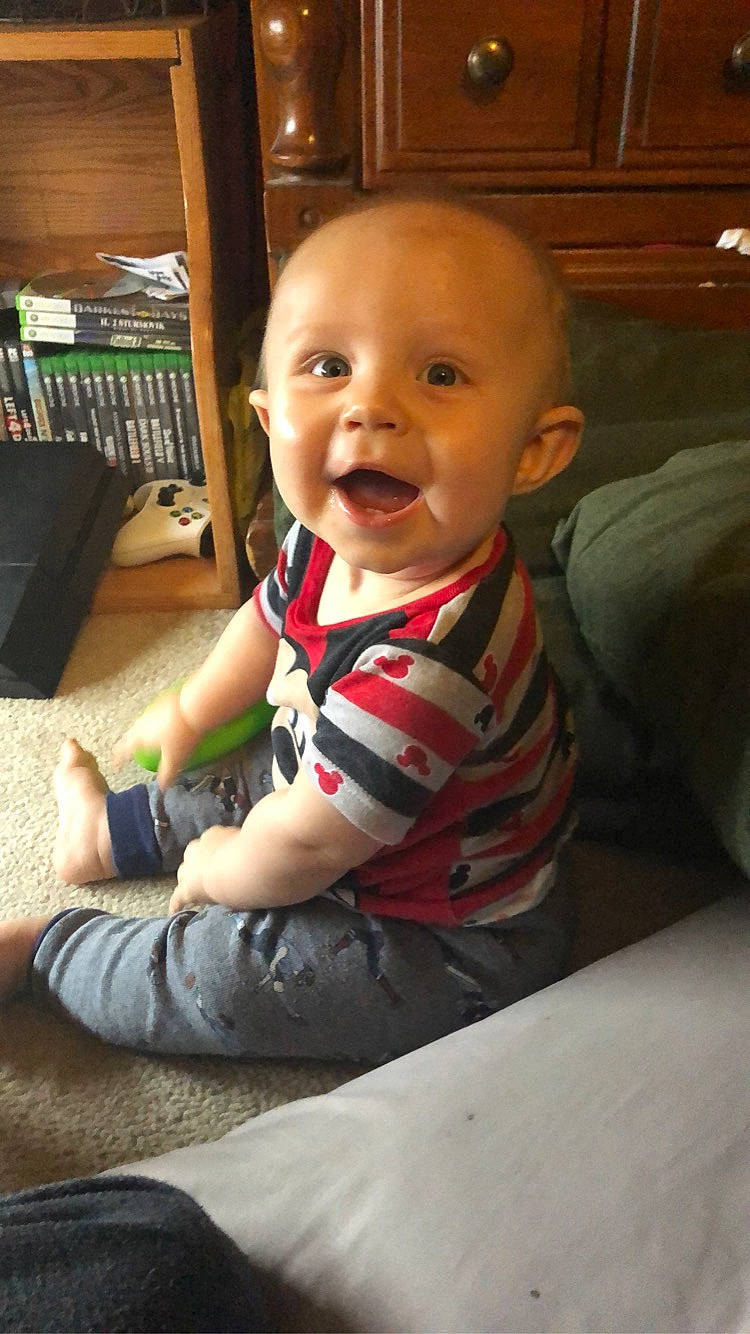 Deacon is registered to the contest to win money with this photo: baby, baby_toddler_clothing, cabinetry, cheek, child, clothing, comfort, finger, floor, flooring, happy, hardwood, person, product, skin, sleeve, smile, standing, t_shirt, toddler