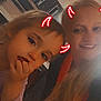 Izabella joined the competition — help win amazing prizes! child, adult, face, indoor, devil_horns, filter, smile, blonde_hair, long_hair, posing, fun, casual, person, portrait, hand_on_face, warm_lighting, kitchen_background, cabinet, red_horns, digital_effect