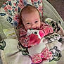 baby, infant, smiling, plush_toy, blanket, floral_pattern, seated, indoor, cute, happy, child, soft_toy, car_seat, cozy, pink, clothing, face, person, toy, young