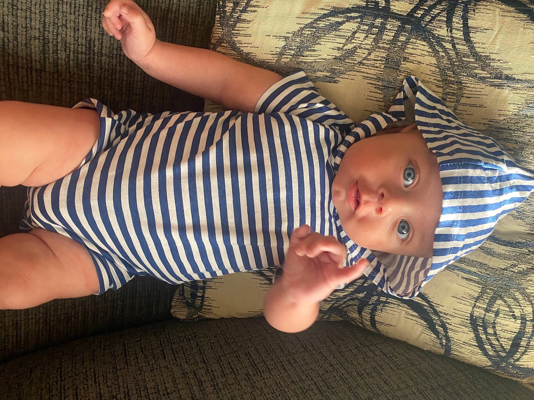 Bennett is registered to the contest to win money with this photo: baby, baby_toddler_clothing, cool, elbow, electric_blue, facial_expression, finger, flooring, grass, headwear, human_body, human_leg, knee, pattern, person, sitting, skin, textile, thigh, toddler