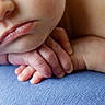 baby, close_up, face, hands, infant, skin, lips, resting, blue_surface, texture, softness, newborn, detail, portrait, peaceful, cute, small_fingers, sleepy, child, human