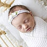 newborn, baby, sleeping, white_blanket, headband, flower, pillow, crib, wooden_crib, infant, peaceful, wrapped, soft_lighting, portrait, closeup, cute, face, resting, indoors, baby_girl
