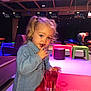 toddler, child, drinking, glass, straw, bowling_alley, colorful, pigtails, blue_jacket, table, red_table, seating, indoor, person, casual_clothing, fun, recreation, leisure, young_child, activity
