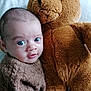 baby, teddy_bear, plush_toy, knitted_sweater, blue_eyes, cuddling, soft_texture, indoor, portrait, child, cute, infant, close_up, warm, comfort, toy, sleepy, face, expression, friendship
