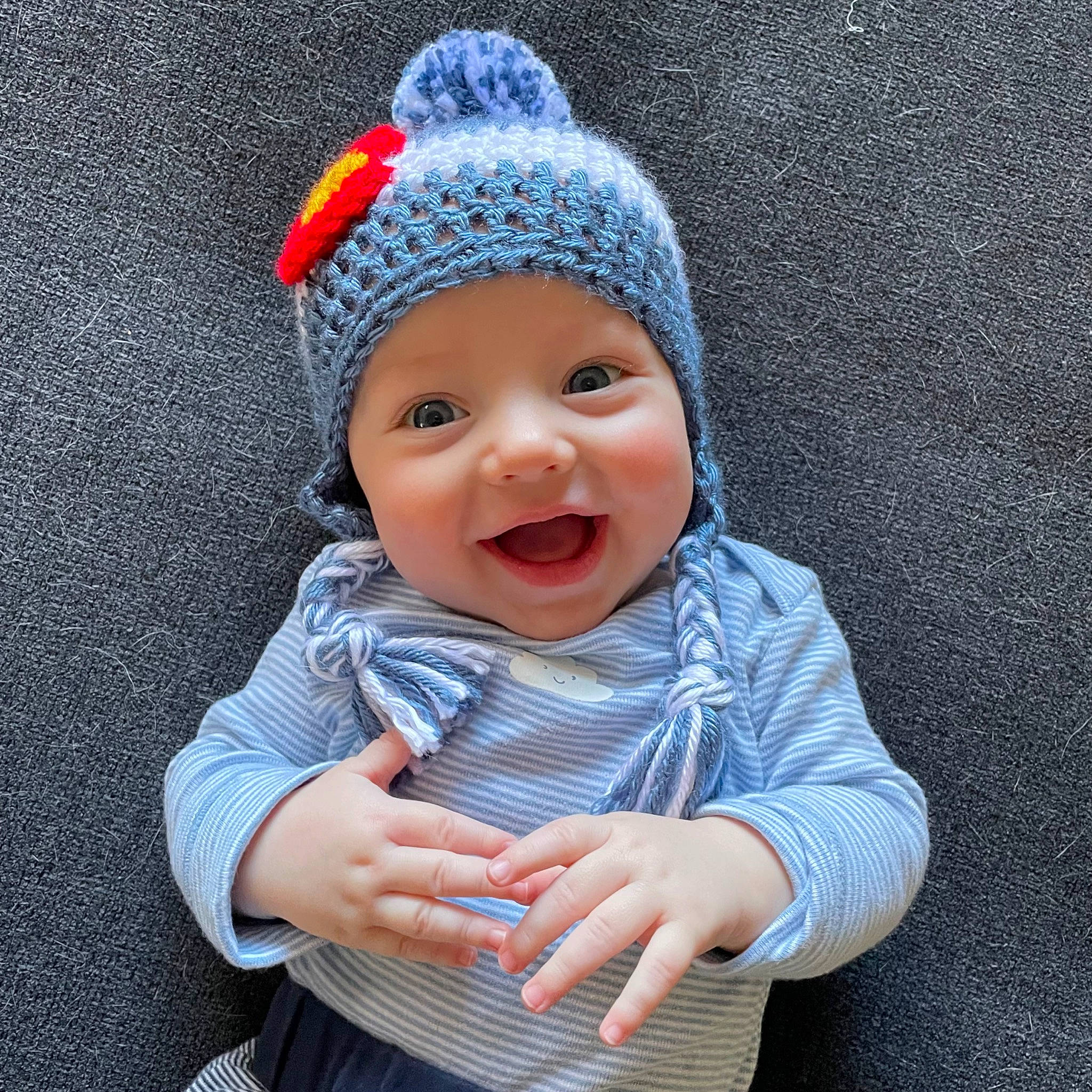 Trace is registered to the contest to win money with this photo: baby, baby_laughing, baby_toddler_clothing, cap, child, clothing, costume_hat, electric_blue, fun, gesture, happy, headgear, headwear, human_body, knit_cap, outerwear, pattern, person, sleeve, smile
