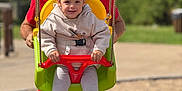 Svetlana a rejoint le concours — aidez-le/la à gagner de superbes lots ! child, toddler, man, swing, playground, outdoor, happy, smiling, casual_clothing, sneakers, rope, red_shirt, yellow_swing, green_swing, shorts, daylight, grass, blurred_background, person, fun